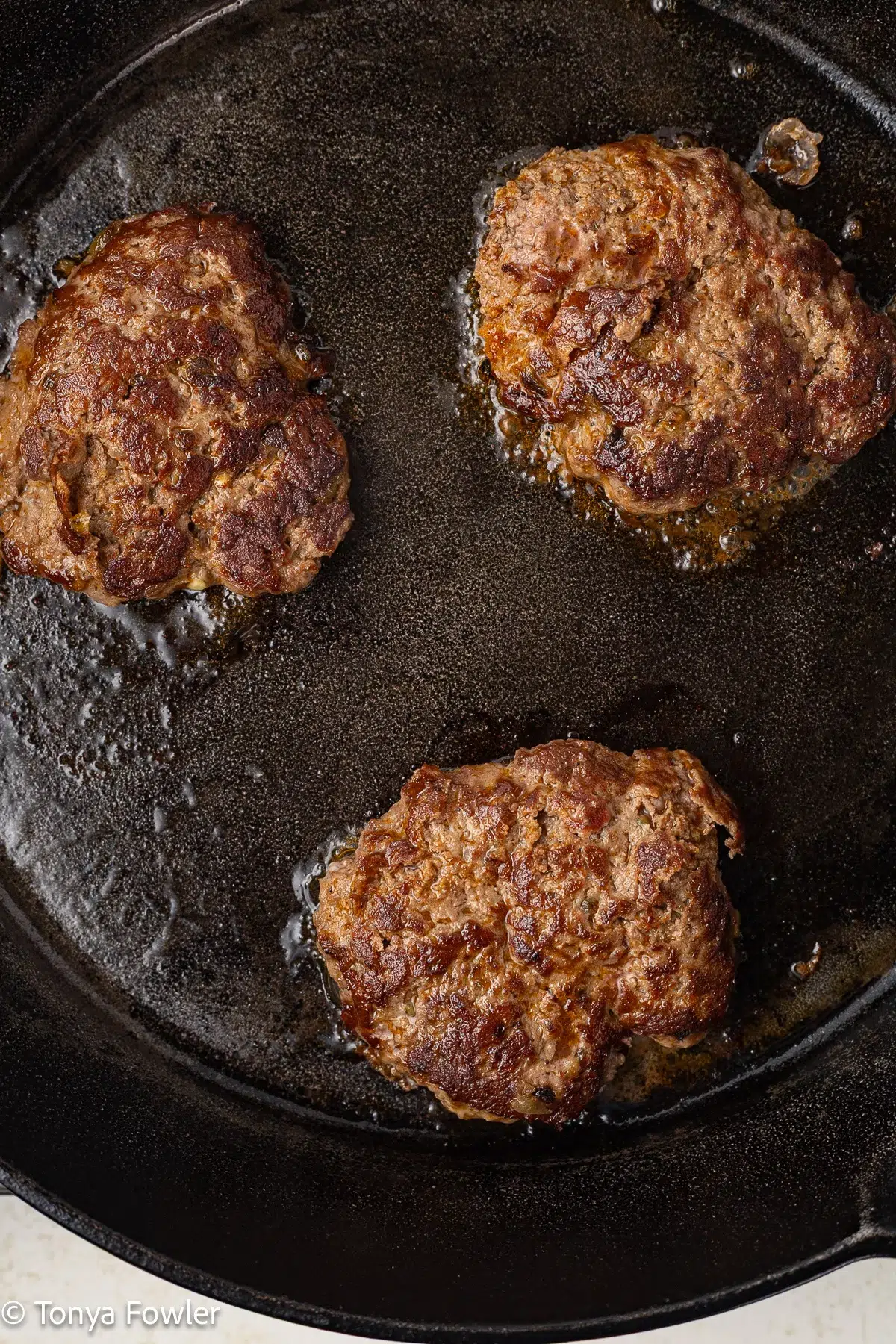 Cooked burgers in a cast iron skillet.