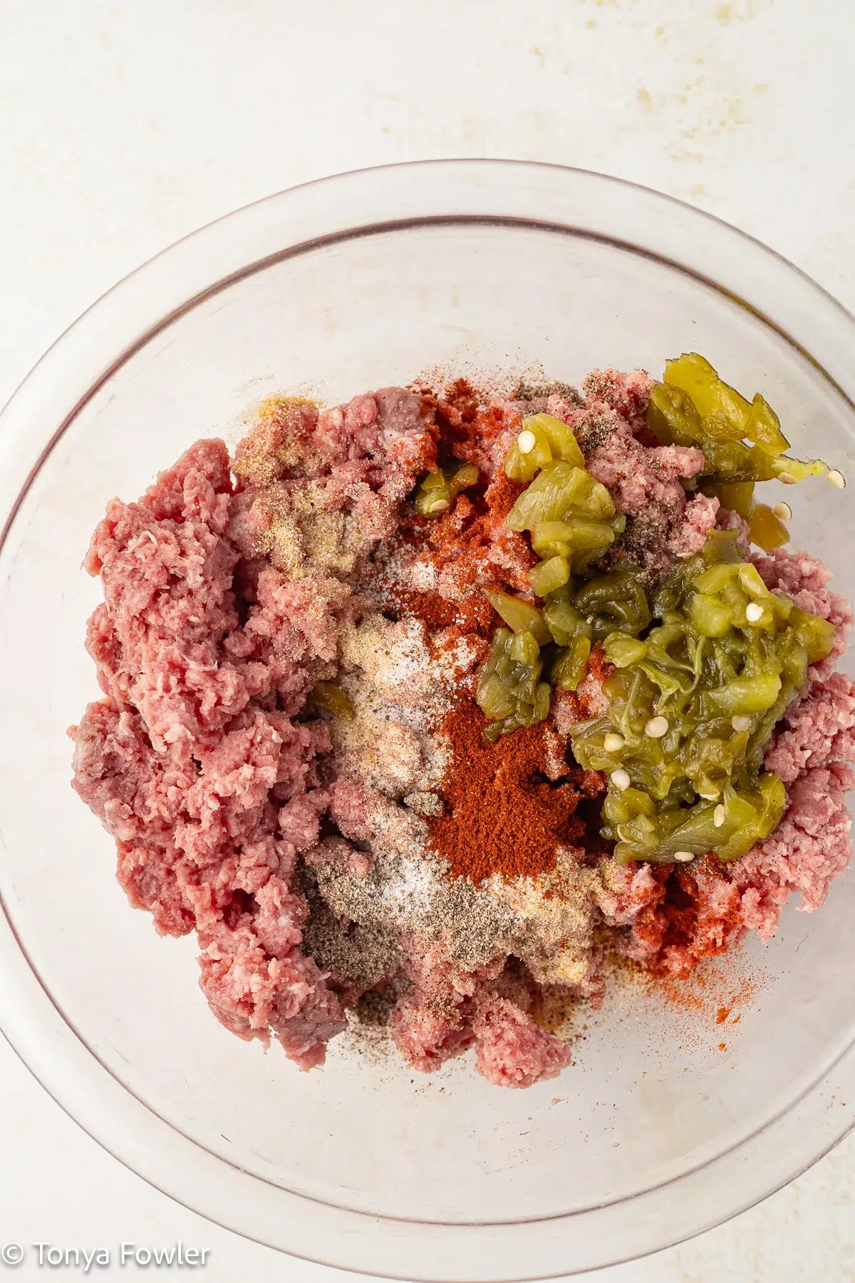 Raw meat and seasonings in a bowl.