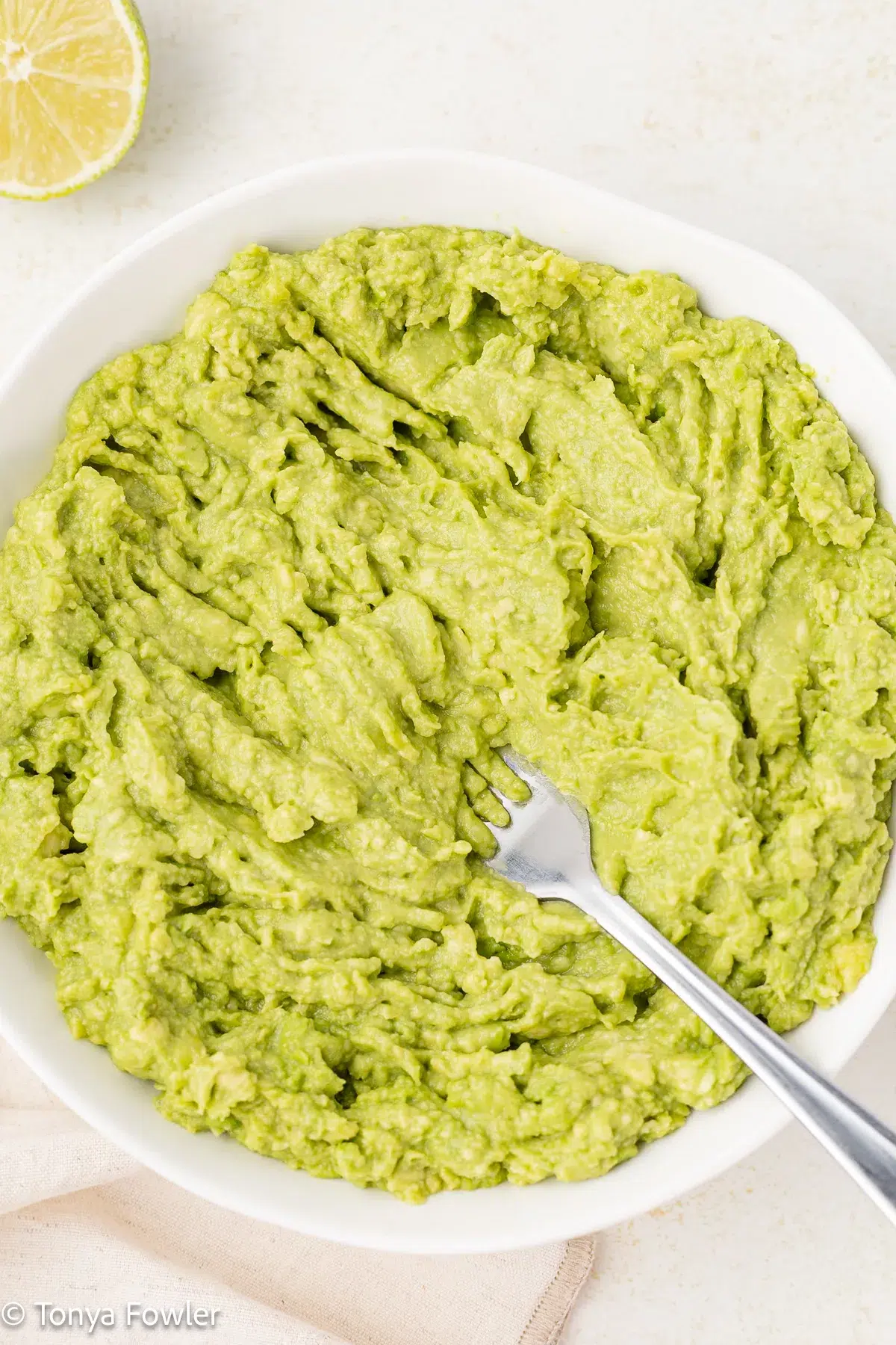 Mashed avocados in a bowl with a fork.