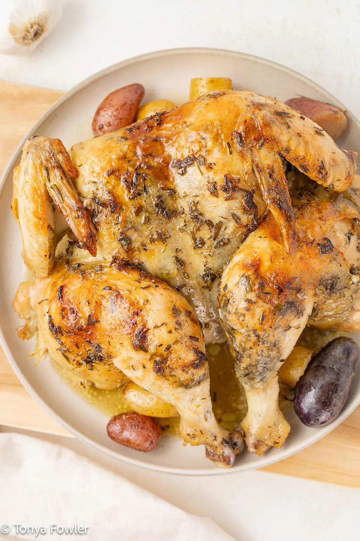 Spatchcocked chicken on a plate with potatoes.
