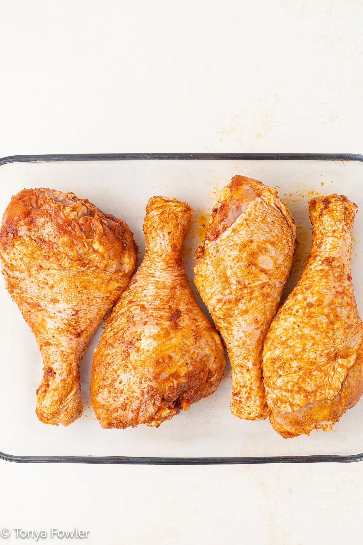 Seasoned raw turkey legs in a baking dish.