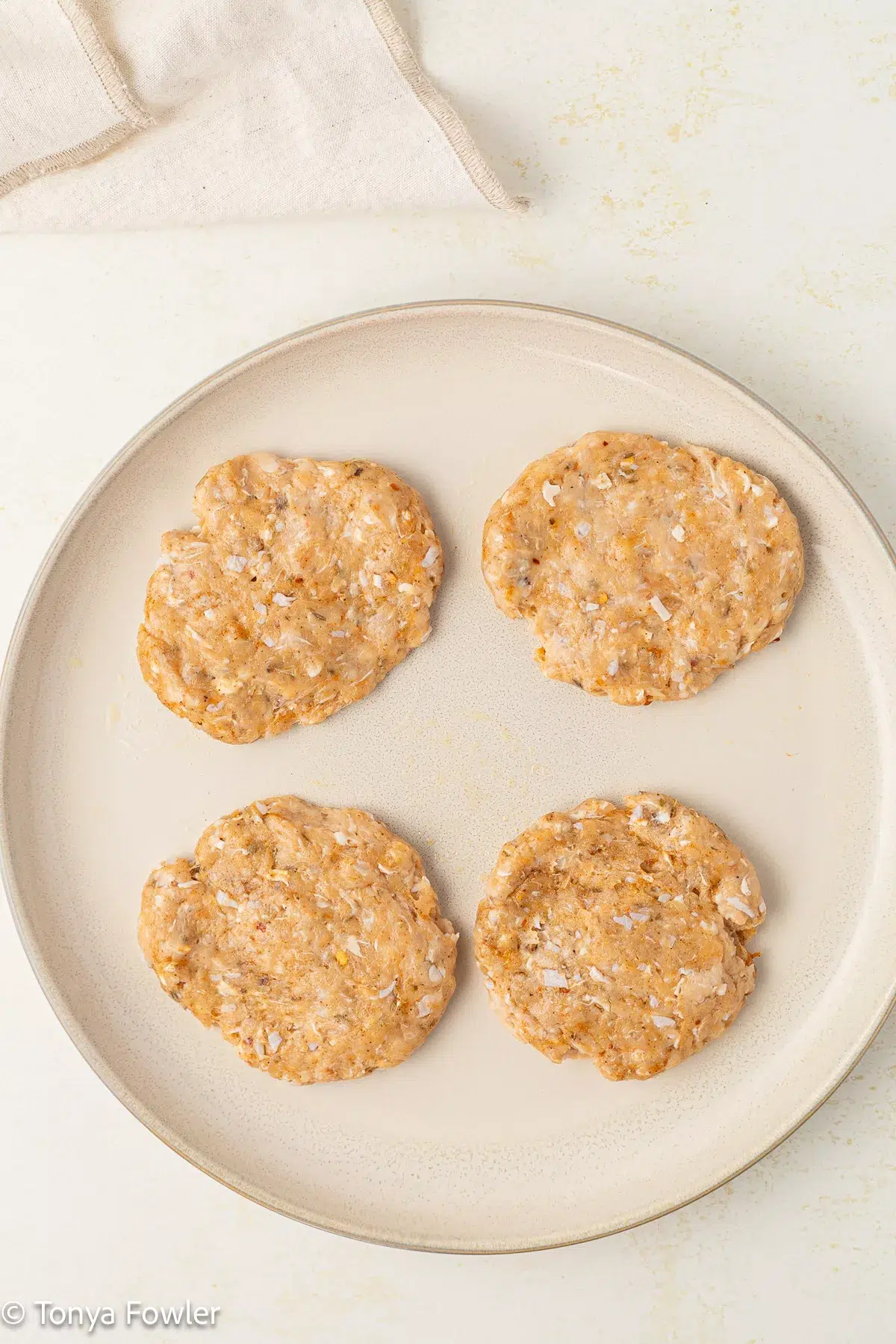 Raw chicken sausage patties on a plate.