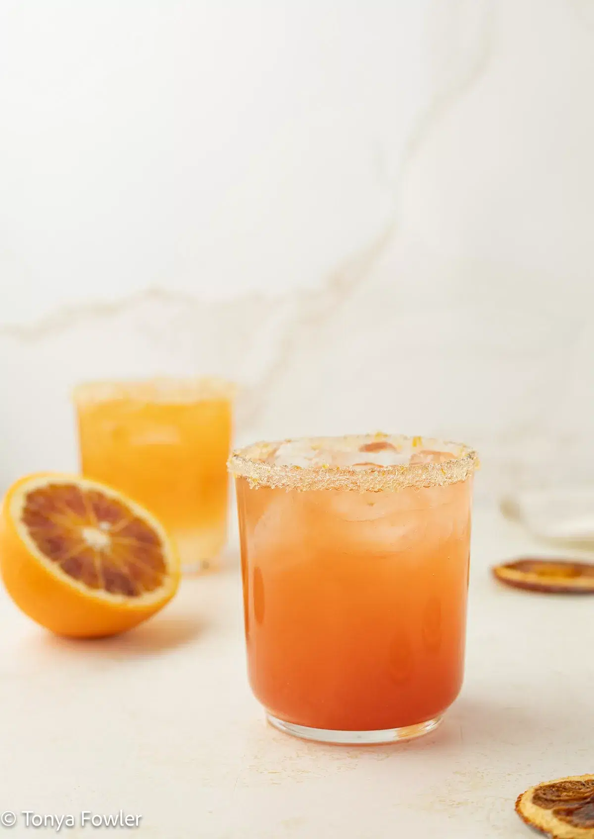 Blood Orange Ginger Mocktails in a glasses with fresh and dried blood oranges on the counter near by.