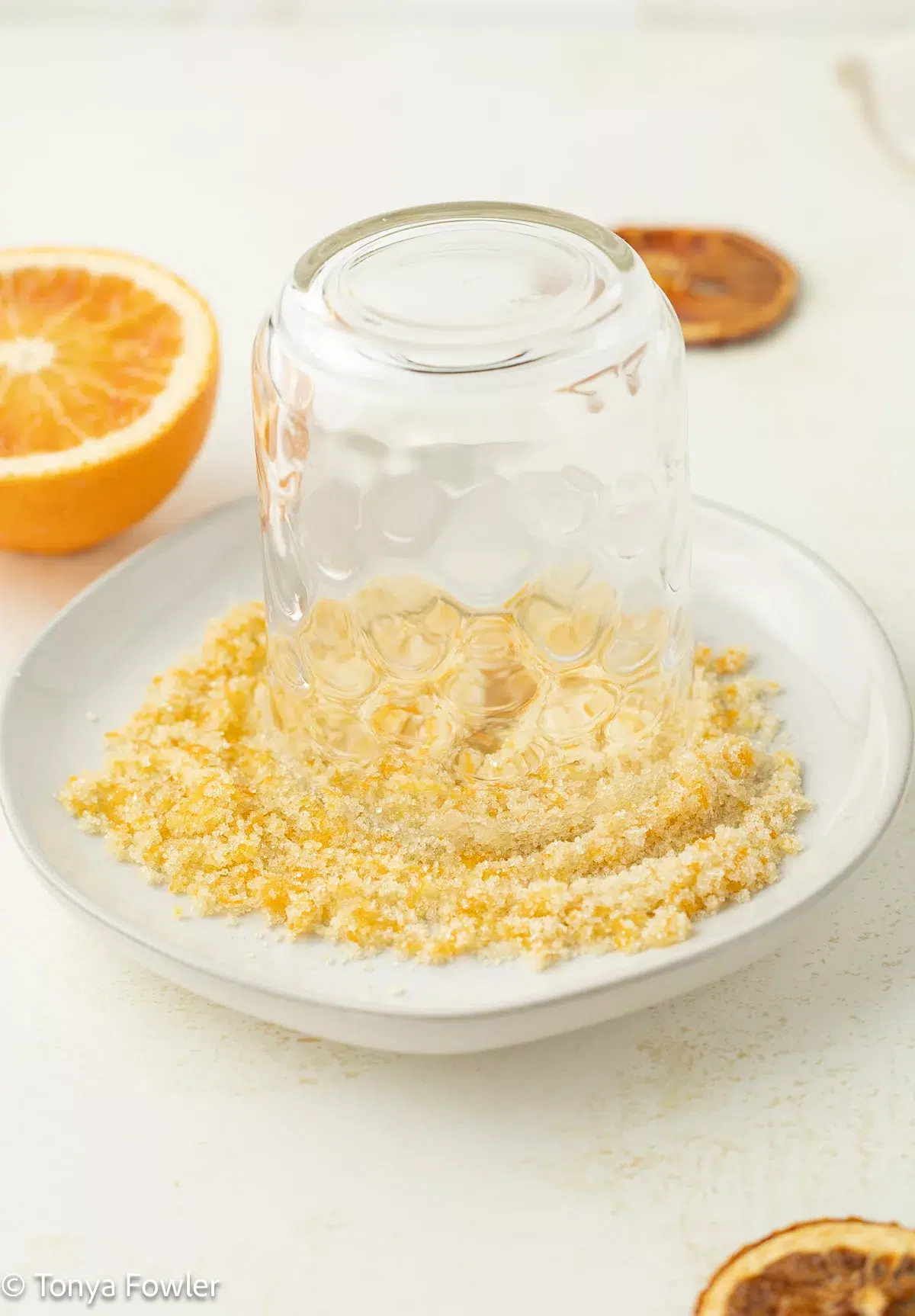 A cup on a plate with orange zest and sugar to make a sugar rim.