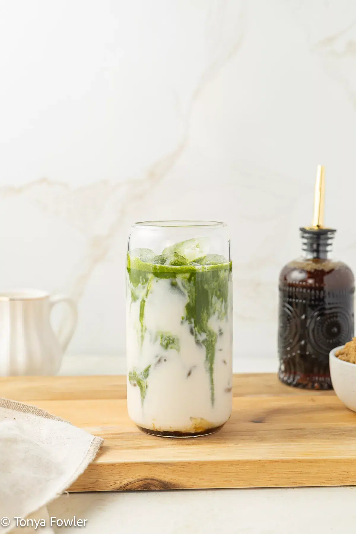 Milk and ice in a glass with matcha poured on top.