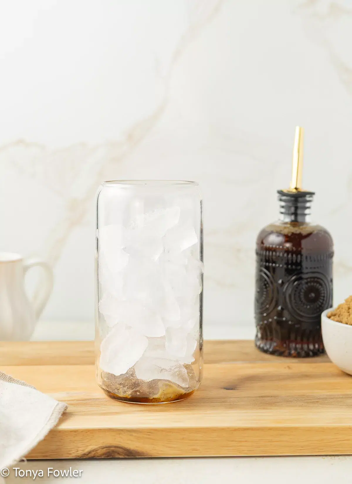 Ice and brown butter syrup in a glass.
