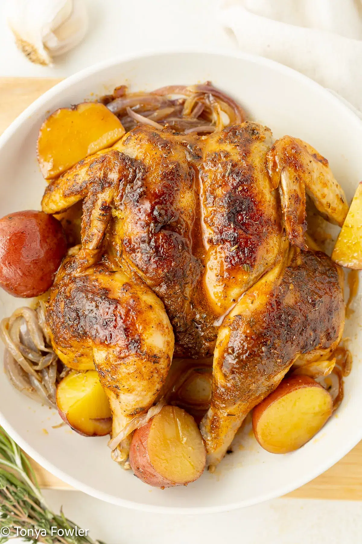 Cajun cornish hen on a plate with potatoes and onions.