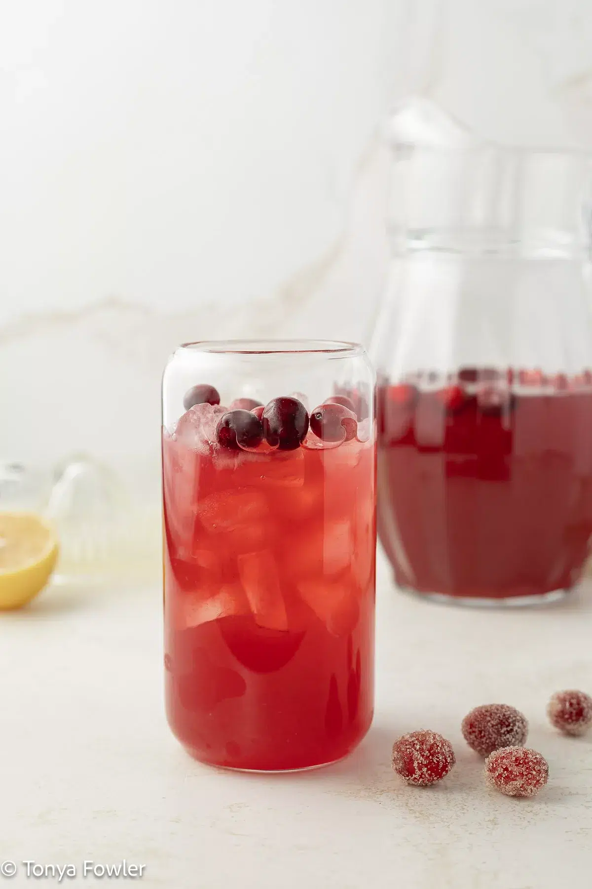 Cranberry lemonade in a glass with ice and cranberries.