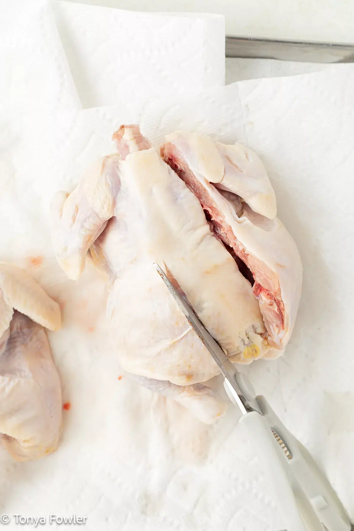 Process image of a cornish hen being spatchcocked.