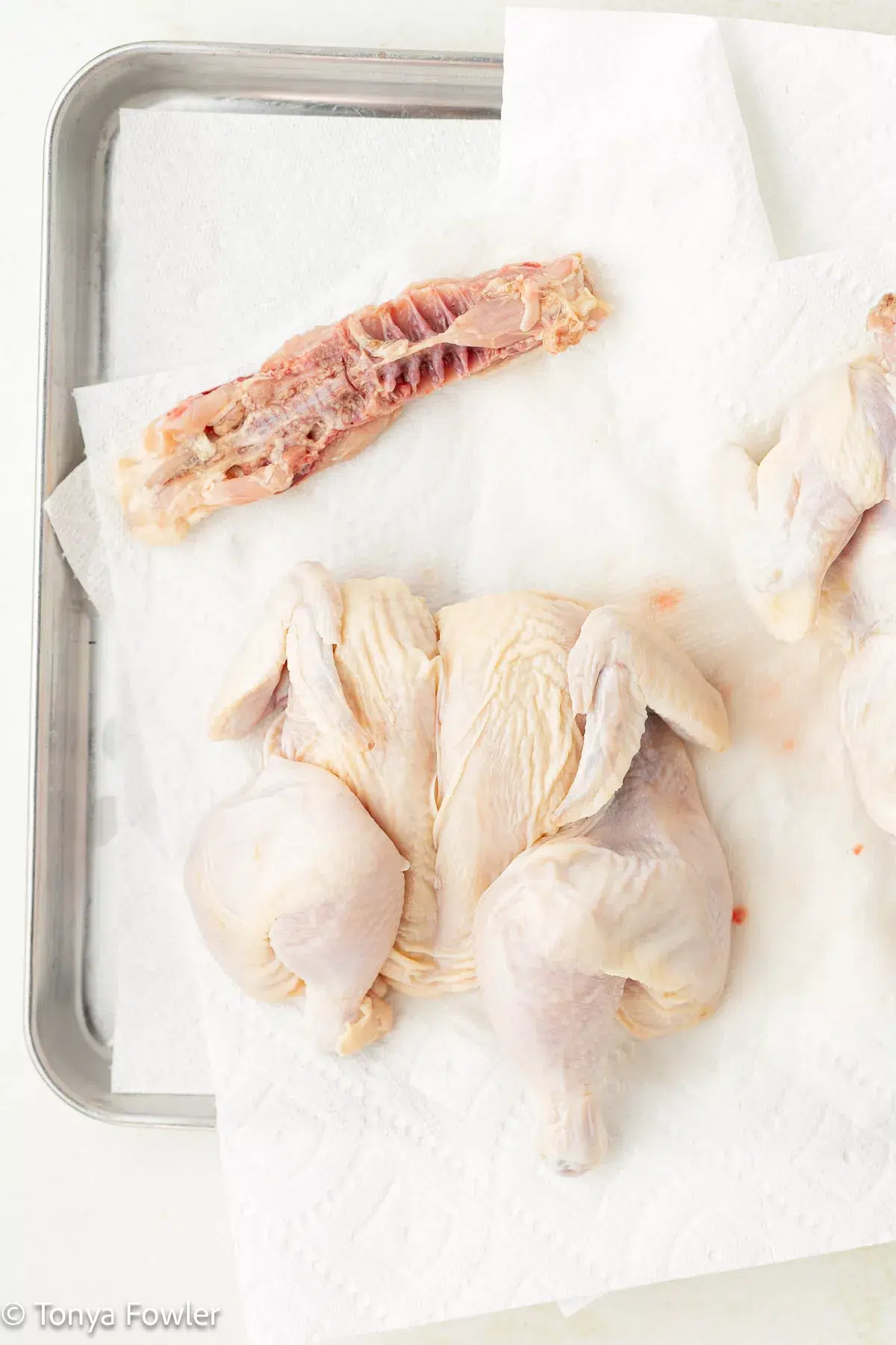 A spatchcocked cornish hen on a sheet pan.
