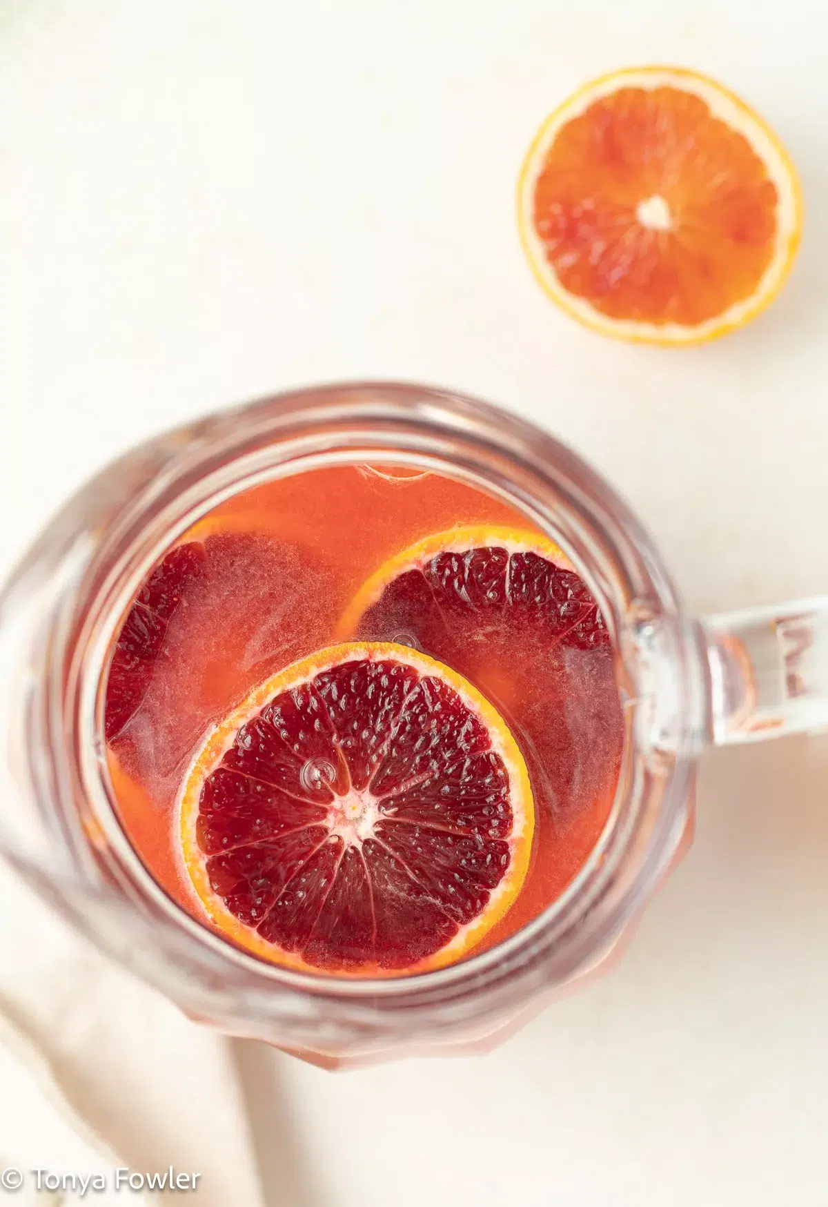 Blood orange lemonade in a pitcher with slices of blood oranges.