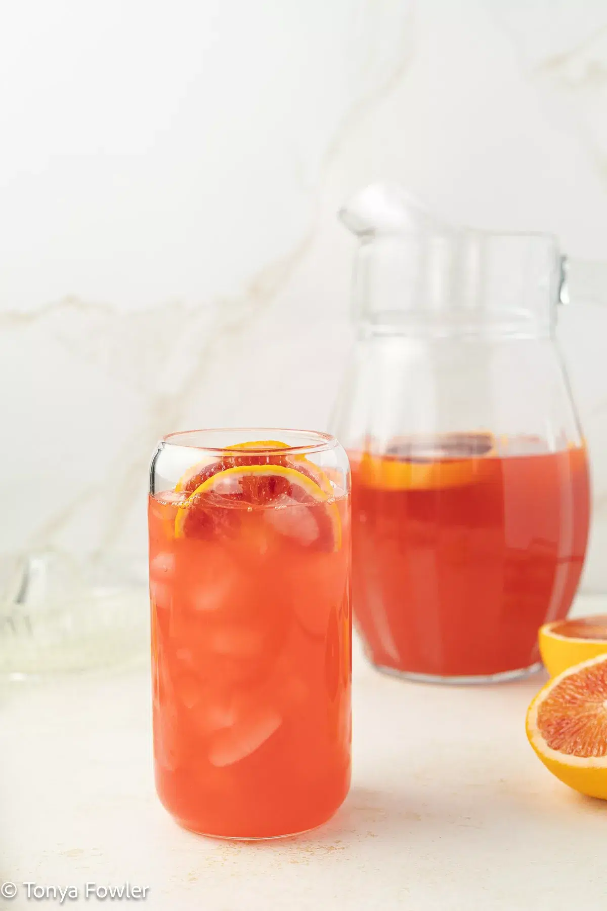 A glass of blood orange lemonade on a counter.