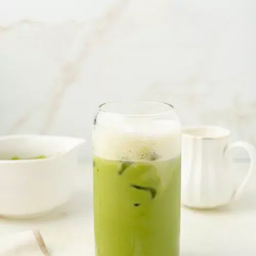 Matcha latte in a glass topped with protein milk.