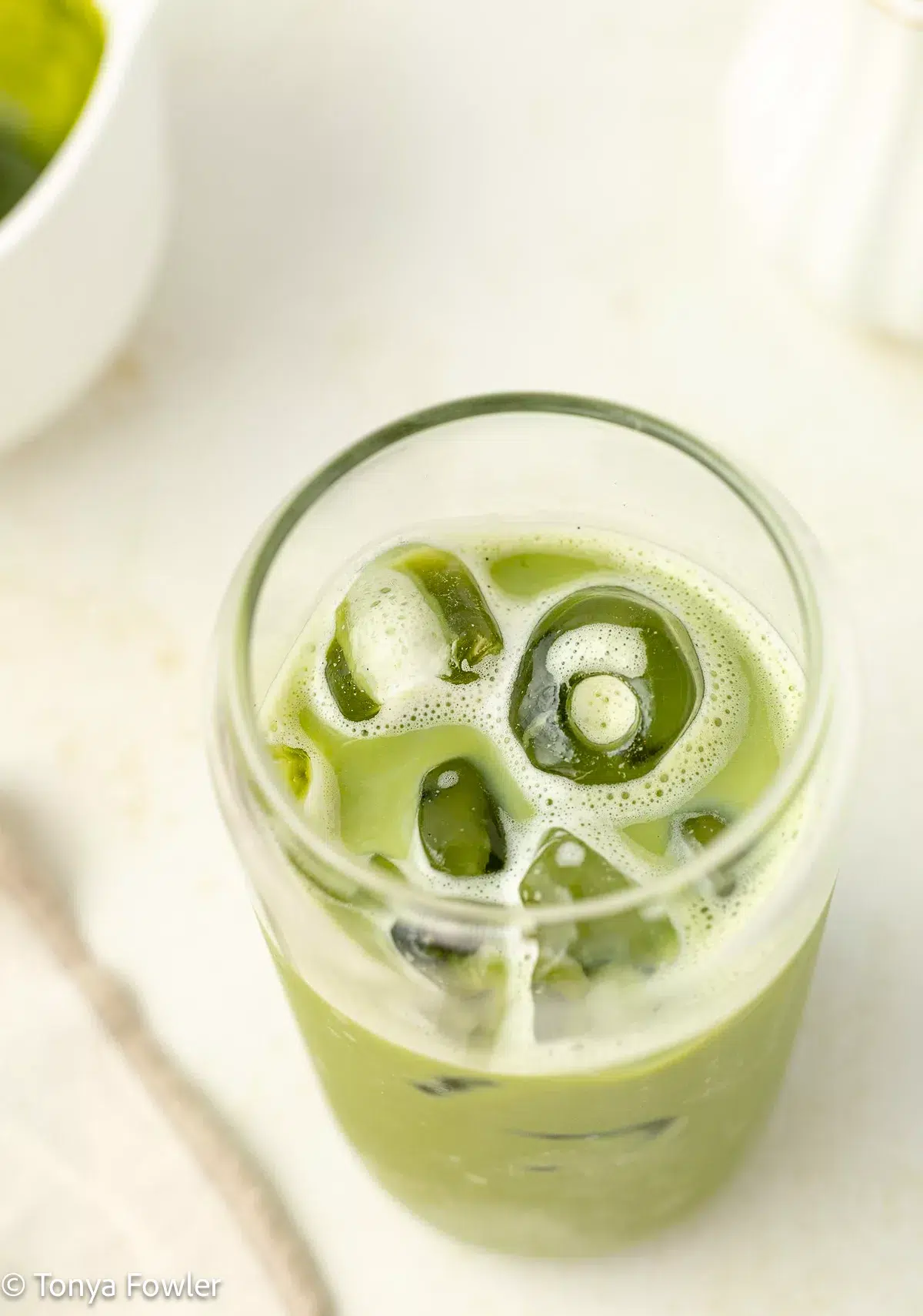 Close up image of a matcha drink with ice in a glass.