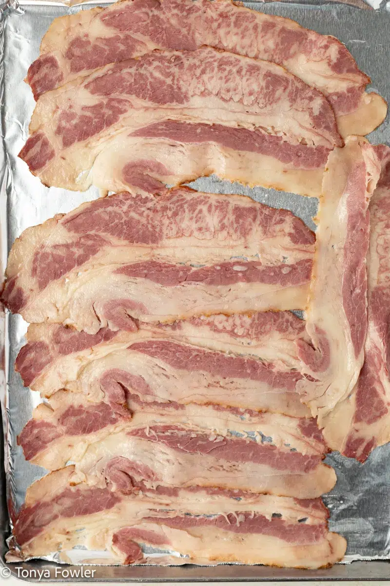 Raw bacon on a sheet pan.