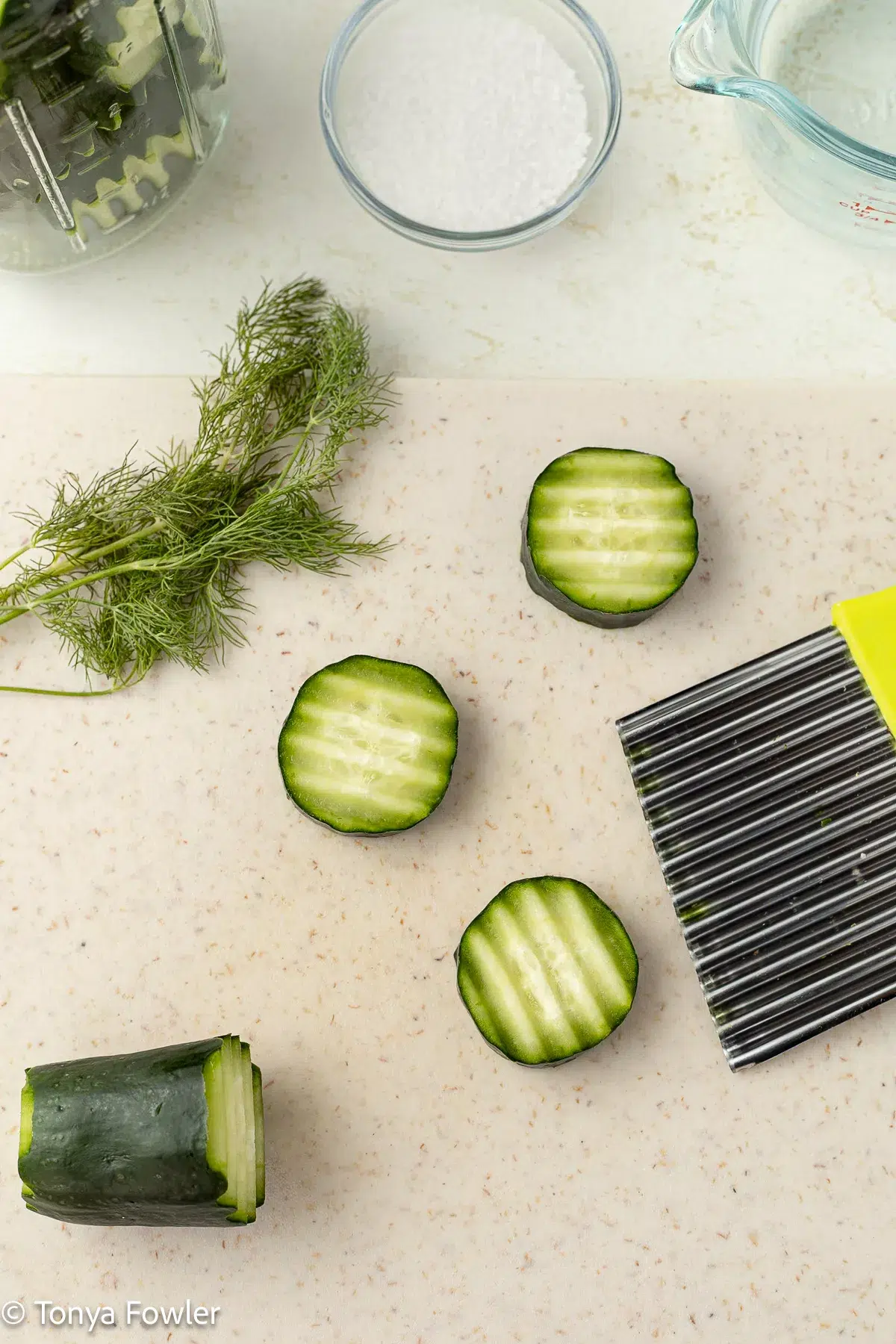 Cut cucumbers on a cutting board with fresh dill.
