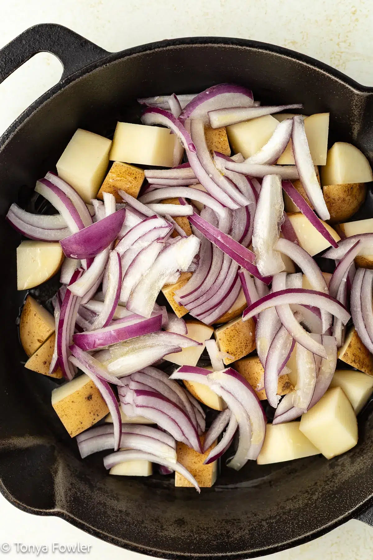 Onions and potatoes in a cast-iron skillet.