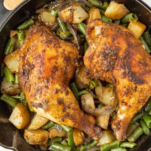 Cooked chicken, potatoes and green beans in a cast iron skillet.