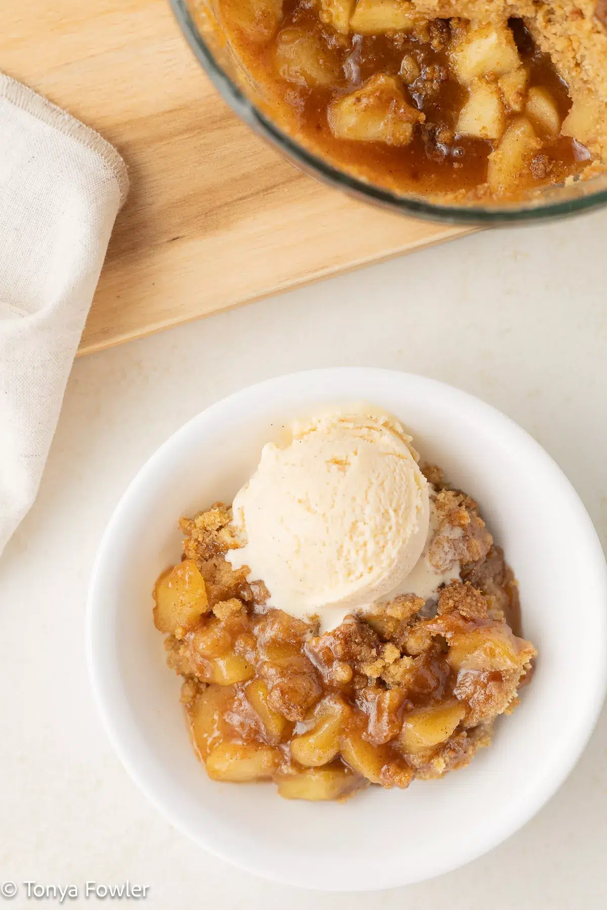 Freshly milled apple crumble in a bowl topped with a scoop of ice cream.