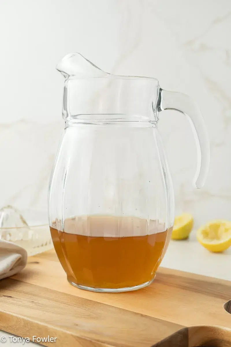 Green tea in a pitcher sitting on a cutting board.