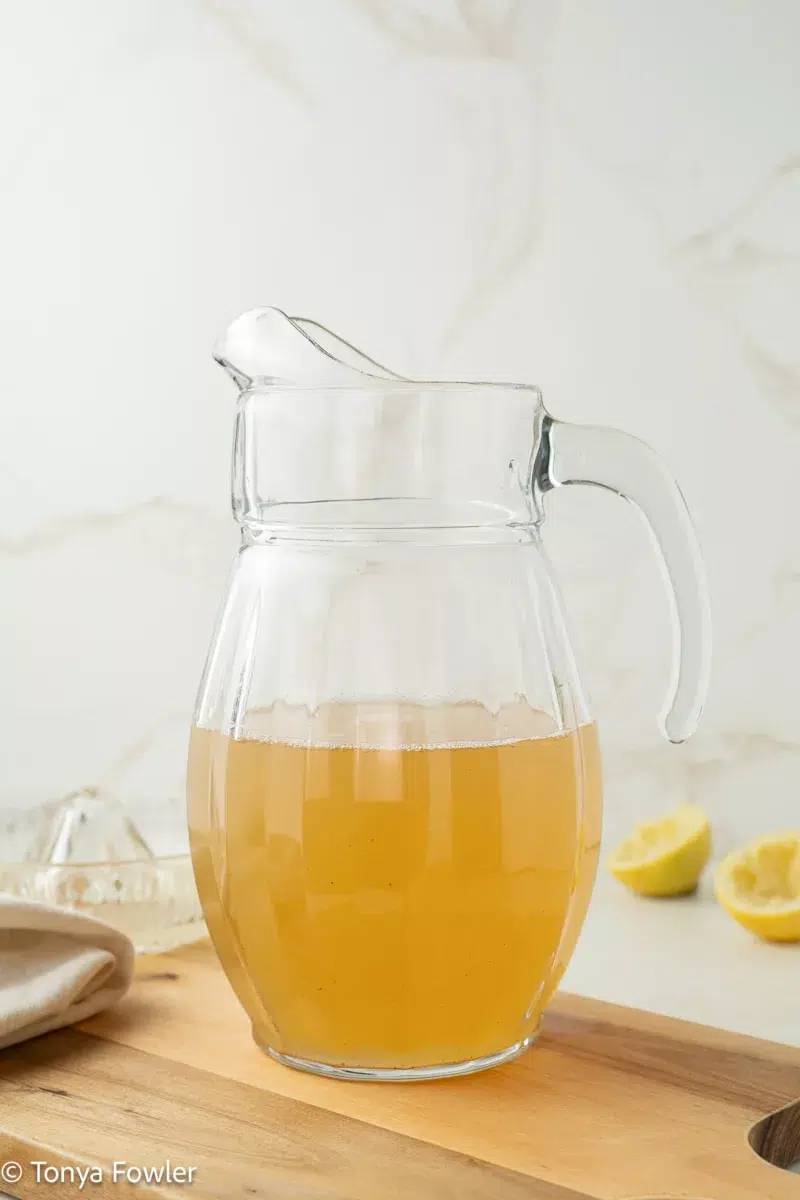Green tea lemonade in a pitcher sitting on a cutting board.