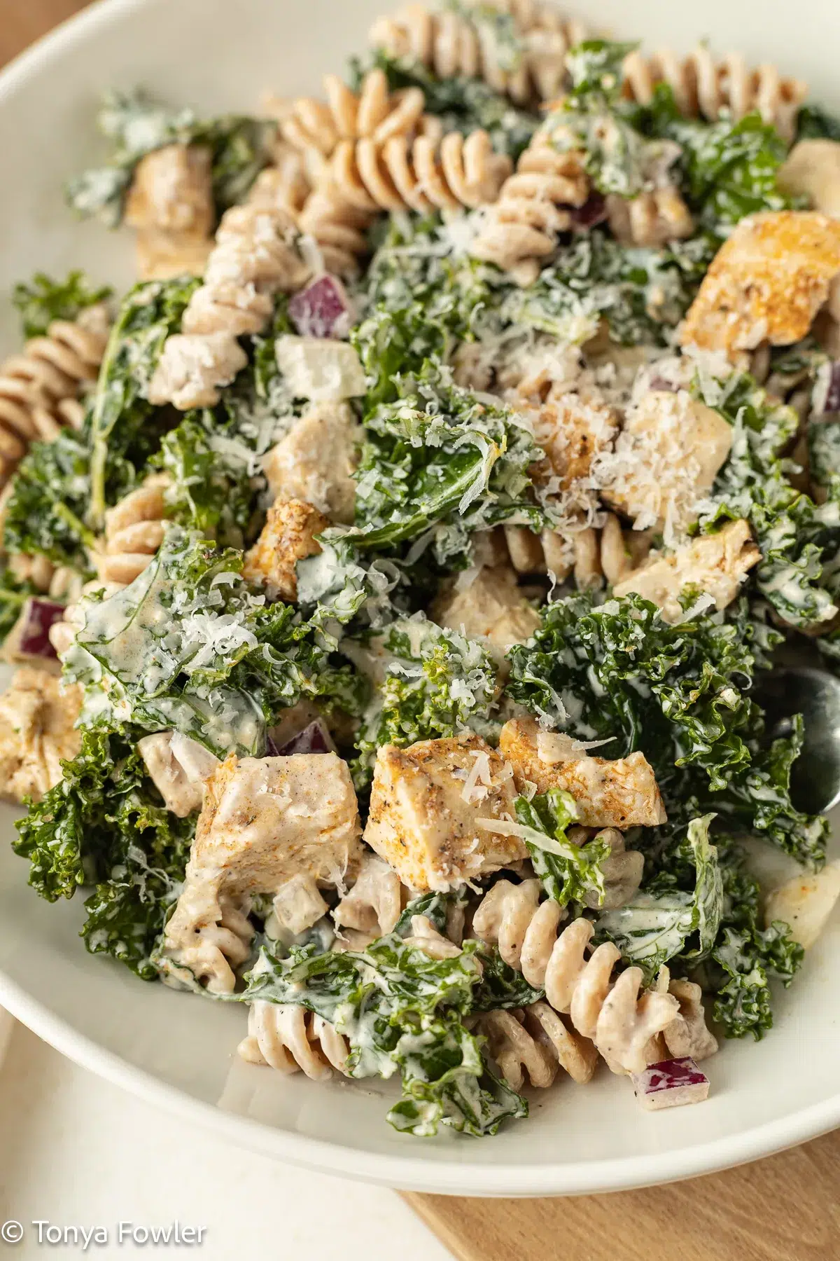 Close up image of kale chicken caesar pasta salad on a plate.