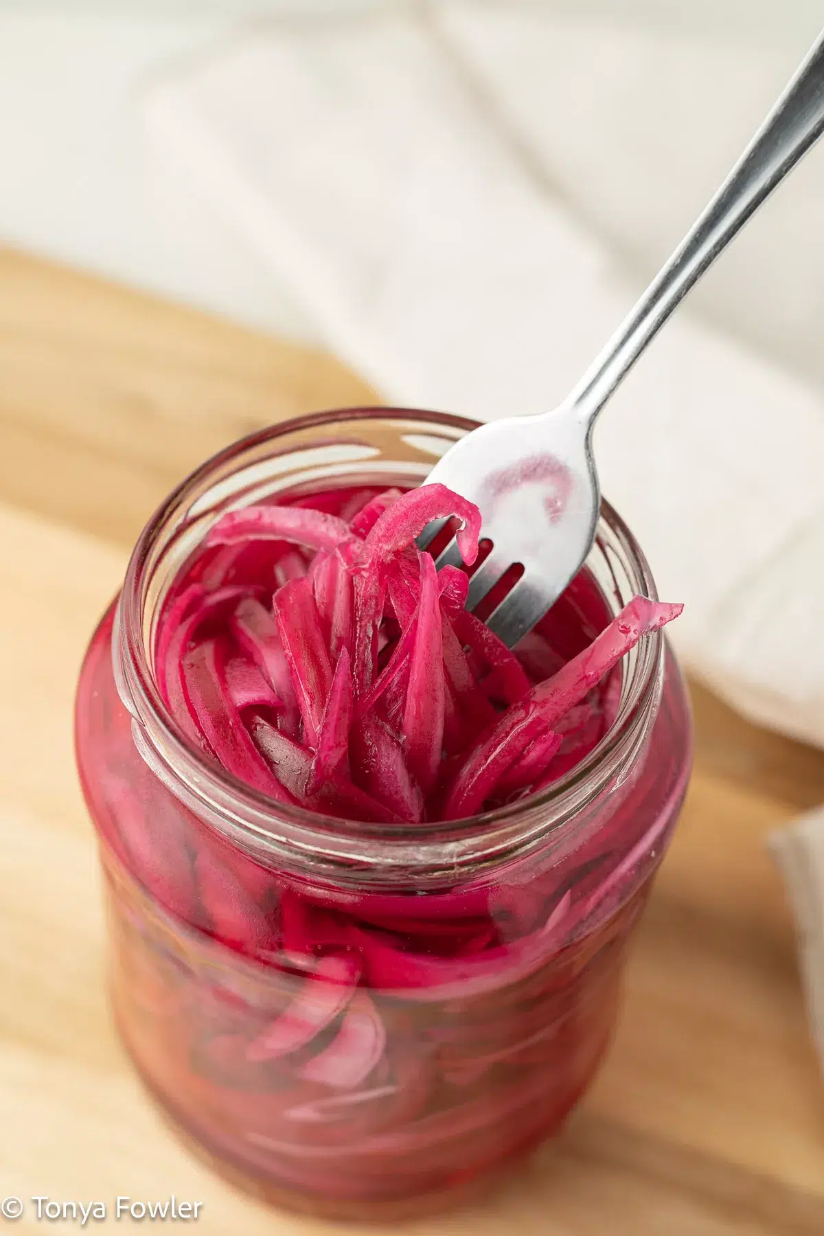 Pickled red onions in a jar with a fork.