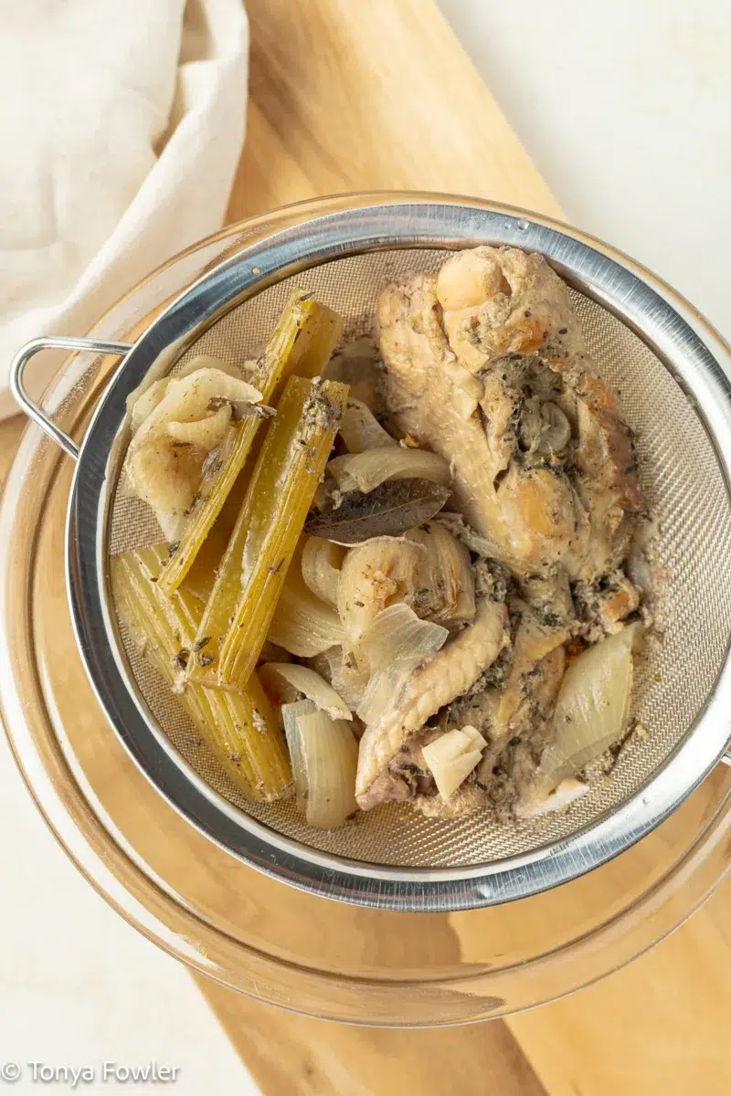 Chicken broth being strained into a bowl.